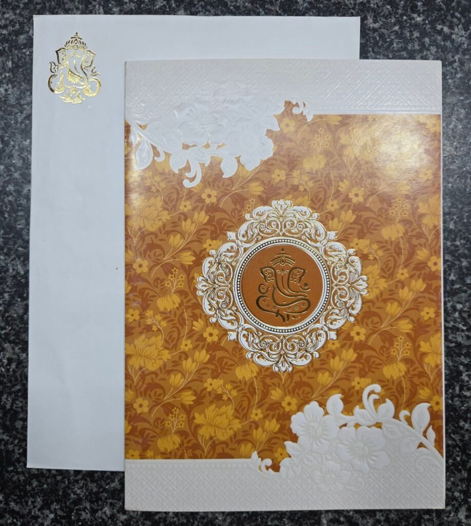 An elegant mustard-gold floral pattern and Ganesha motif Wedding Card